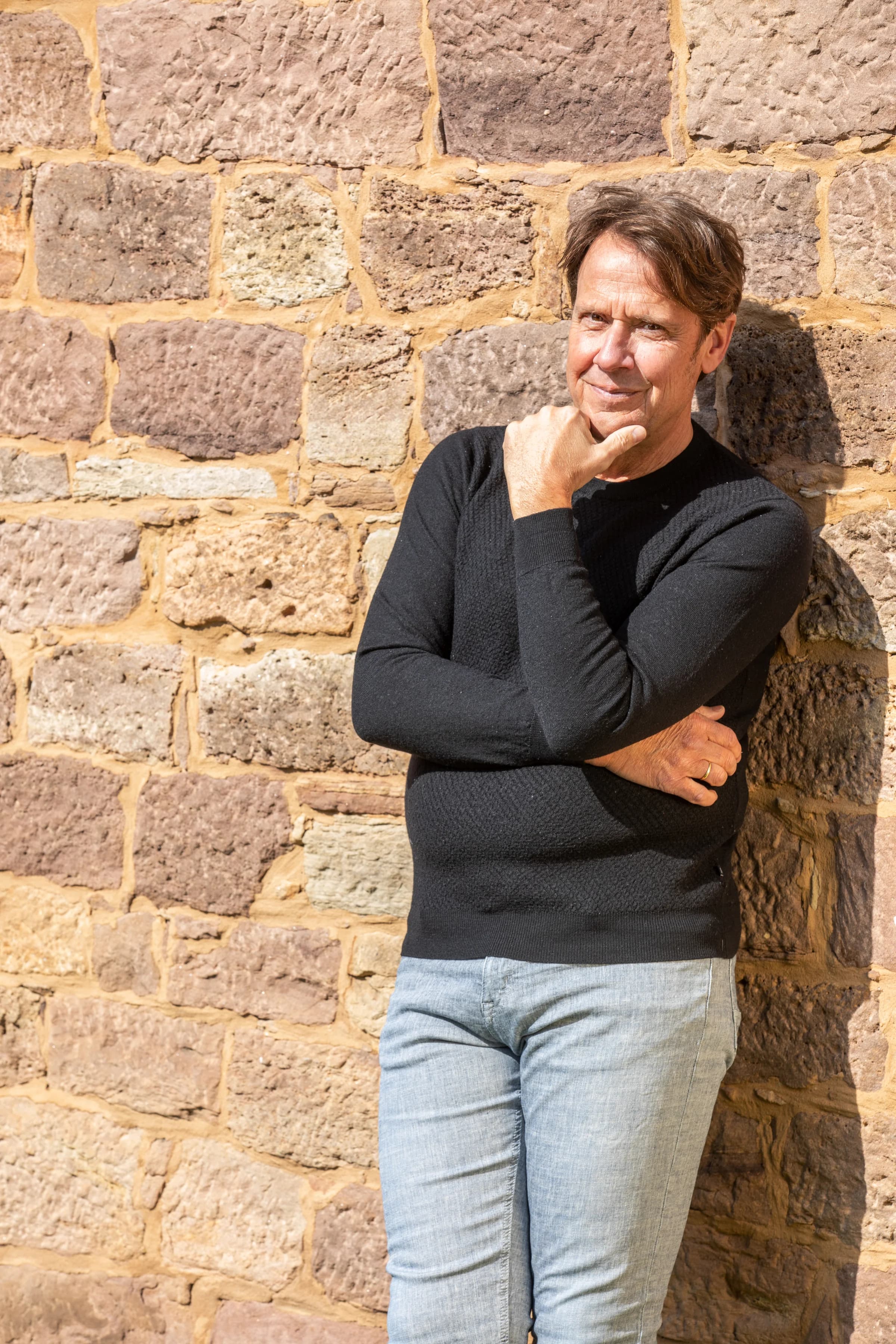 Dr. phil. Christoph Quarch, angelehnt an eine Sandsteinmauer