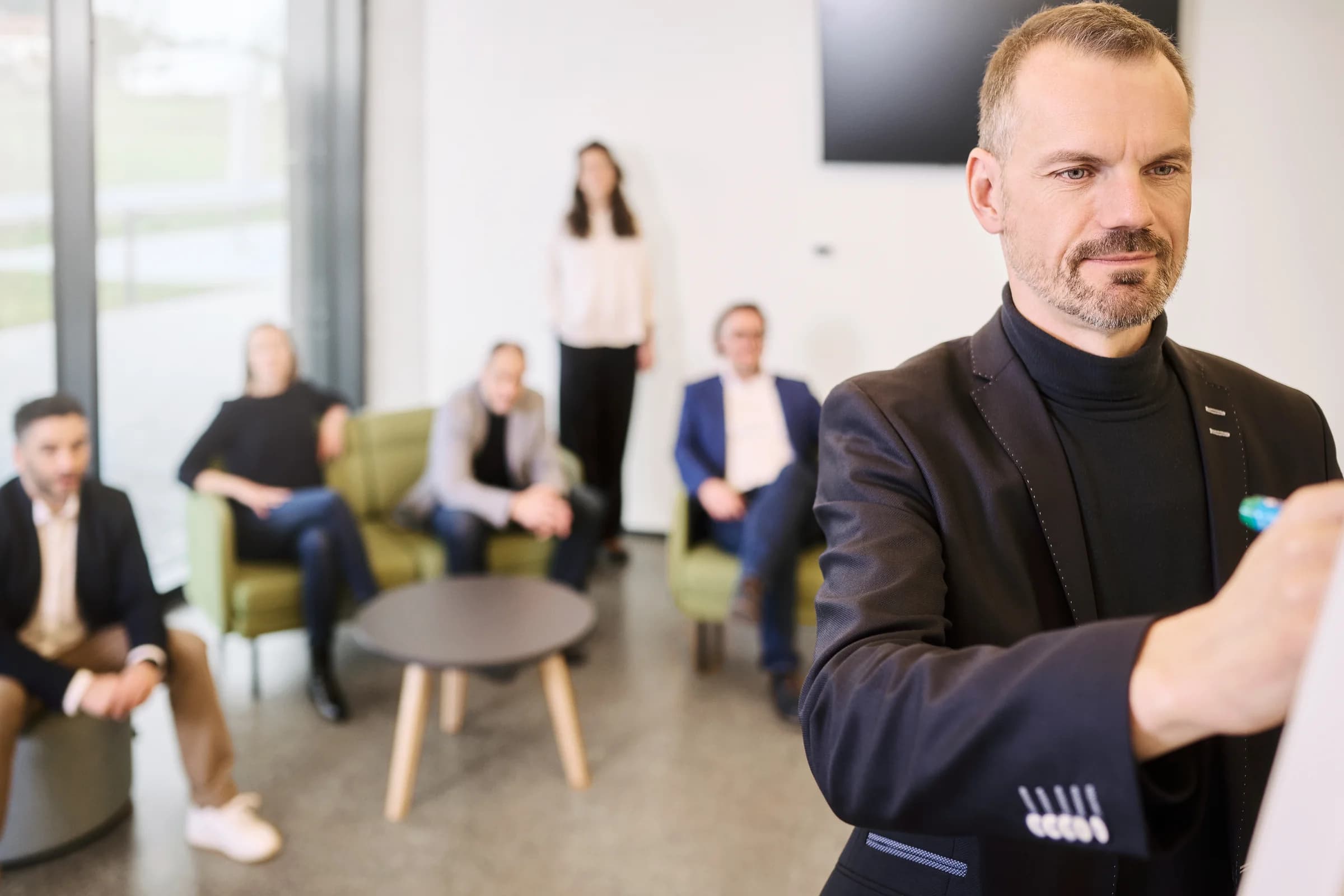 Stefan Reith schreibt am Flipchart, die Workshopgruppe im Hintergrund